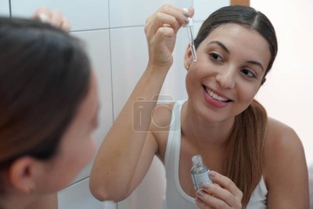 Hautpflege-Routine. Nahaufnahme einer schönen Frau mit einer Pipette in der Hand und einem feuchtigkeitsspendenden Anti-Aging-Antioxidans.