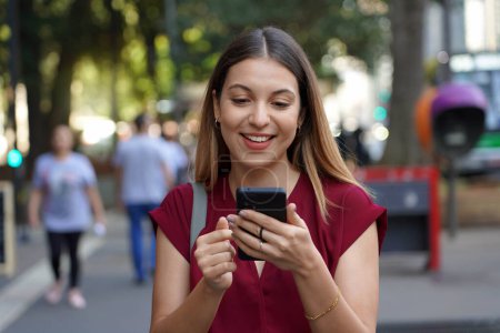 Photo for Close-up of young stylish woman using smartphone with ring holder to avoid thefts on the street in the metropolis with blurred people on the background - Royalty Free Image