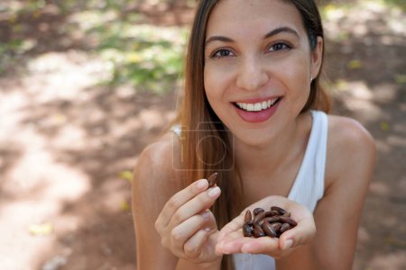 Foto de Primer plano de la mujer sana comiendo semillas de baru en el parque. Mira la cámara.. - Imagen libre de derechos