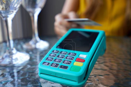 Téléchargez les photos : Extrême gros plan d'un client méconnaissable utilisant une carte de crédit pour le paiement en ligne. NFC paiement sans contact par carte de crédit et pos terminal au café. - en image libre de droit