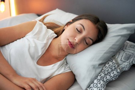 Foto de Importancia neurocientífica de un buen sueño. Joven hermosa mujer duerme felizmente en la cama. Chica con ciclo circadiano regulado. - Imagen libre de derechos
