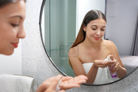 Beautiful young woman spraying cleansing oil on her hand, eco-friendly solution to remove makeup. Beauty girl with ecological environmentally friendly makeup remover without cotton pad.