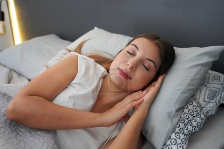 Importance d'un bon sommeil. Jeune belle femme dort joyeusement dans le lit. Fille avec cycle circadien réglementé.