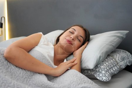 Mujer joven durmiendo en dos almohadas en la cama