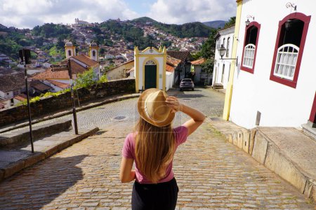 Photo for Holidays in Ouro Preto, Brazil. Back view of traveler woman descends street in the historic city of Ouro Preto, UNESCO World Heritage Site, Minas Gerais, Brazil. - Royalty Free Image