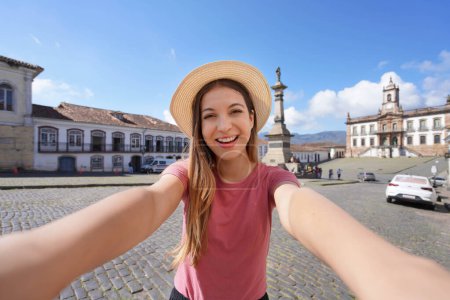 Schöne Reisende Mädchen nimmt Selbstporträt in Tiradentes Square berühmten Wahrzeichen von Ouro Preto, Unesco-Weltkulturerbe im Bundesstaat Minas Gerais, Brasilien
