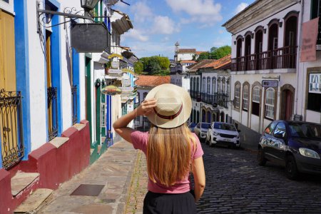 Photo for Holidays in Ouro Preto, Brazil. Rear view of tourist woman descends street in the historic city of Ouro Preto, UNESCO World Heritage Site, Minas Gerais, Brazil. - Royalty Free Image