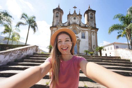 Hermosa turista toma autorretrato en la ciudad colonial barroca de Ouro Preto, antigua capital del estado de Minas Gerais, Brasil, Patrimonio de la Humanidad por la UNESCO