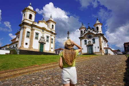 Photo for Holidays in Minas Gerais, Brazil. Back view of traveler girl visiting historical town of Mariana with baroque colonial architecture. Mariana is the oldest city in the state of Minas Gerais, Brazil. - Royalty Free Image