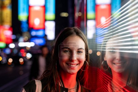 Young beautiful girl walking in Times Square at night. New York City, Manhattan,. High quality photo
