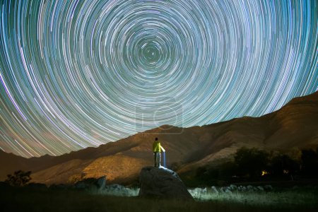 Photo for Rear view of man climbed on a rock looking at star trails at night. High quality photo - Royalty Free Image