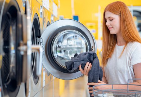 Photo for European woman washing her clothes by a washing machine in laundry shop - Royalty Free Image