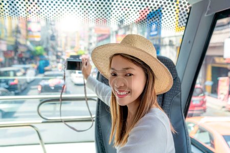 Photo for Asian woman travel and tour in Bangkok city on  yaowarat road area by restaurant bus and take a photo by her smart phone - Royalty Free Image
