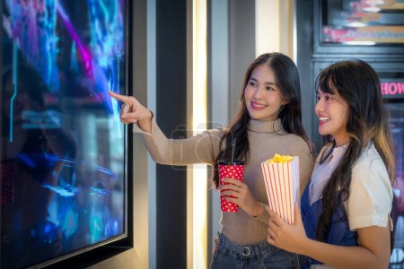 Foto de Feliz grupo de amigos de mujer asiática relajarse e ir a Cimema en el cine juntos y comprar entradas y palomitas de maíz en el servicio de contador de ventas - Imagen libre de derechos