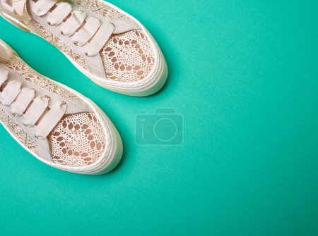 Foto de Zapatillas de punto de diseño pastel de moda con cordones anchos sobre un fondo de papel turquesa con espacio para copiar. Vista superior. Mock-up para cartel publicitario - Imagen libre de derechos