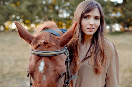 Téléchargez les photos : Sur une prairie de campagne, une jeune femme partage un moment avec son cheval. L'équitation, l'équitation et les sports liés au cheval offrent une gamme d'avantages, y compris la relaxation basée sur la nature. - en image libre de droit