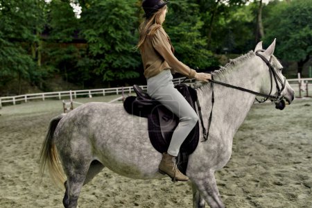 Téléchargez les photos : Cheval gris pomme à l'hippodrome par une jockey femelle. Femme équestre prenant des cours d'équitation à l'école de cheval. Entraînement hippique, dressage hippique, exercices de pas de trot. Mode de vie actif - en image libre de droit