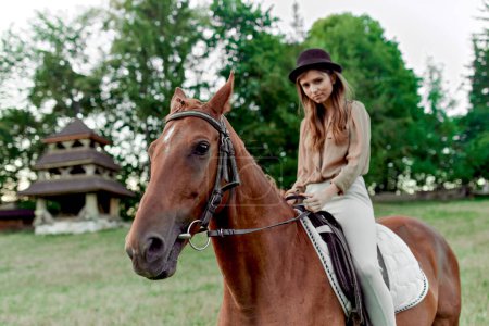 Téléchargez les photos : Femme à cheval à la campagne. Une charmante cavalière à cheval. L'équitation favorise le bien-être, la relaxation. Jeune dame et son cheval déballer des émotions avec une leçon d'équitation - en image libre de droit