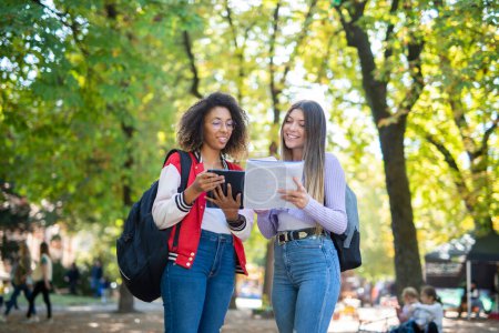 Studentinnen studieren gemeinsam in einem Park in der Nähe ihrer Universität