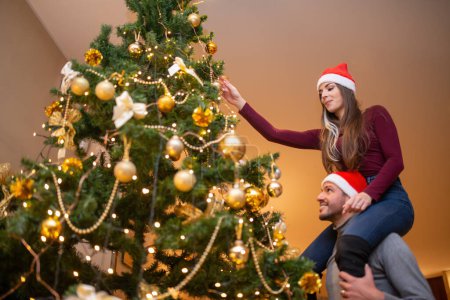 Photo for Couple decorating their Christmas tree at home - Royalty Free Image