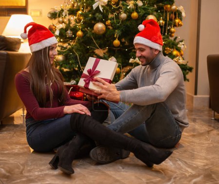 Photo for Young couple opening a Christmas gift - Royalty Free Image