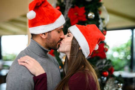 Photo for Beautiful couple kissing and wearing a Santa hat - Royalty Free Image