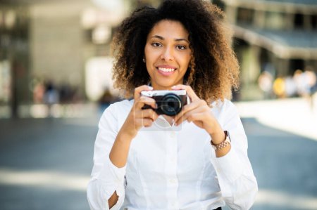 Téléchargez les photos : Portrait of happy afro-american woman taking photos with a mirrorless camera - en image libre de droit