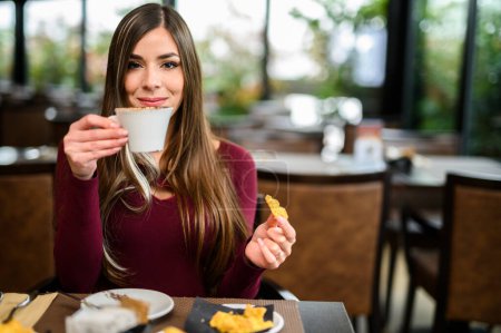 Foto de Mujer joven desayunando en un café - Imagen libre de derechos