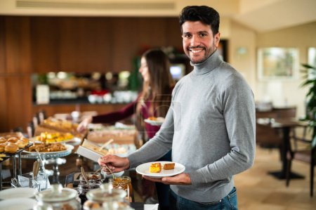 Téléchargez les photos : Man picking food at a buffet in a hotel for his breakfast - en image libre de droit