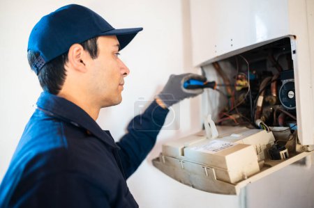 Photo for Smiling technician repairing an hot-water heater - Royalty Free Image