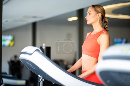 Photo for Young athletic beautiful woman training on a treadmill in the gym - Royalty Free Image