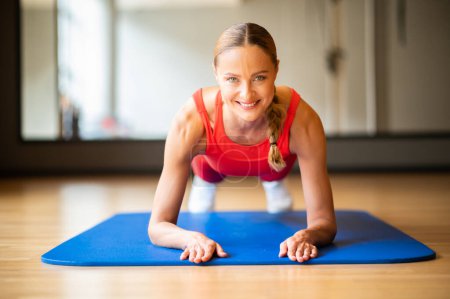 Téléchargez les photos : Woman doing push up exercises on the floor in a gym - en image libre de droit