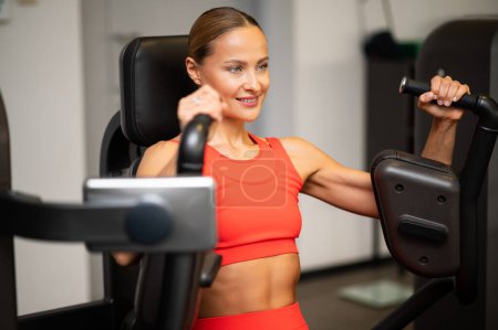 Téléchargez les photos : Femme utilisant une presse thoracique dans une salle de gym - en image libre de droit