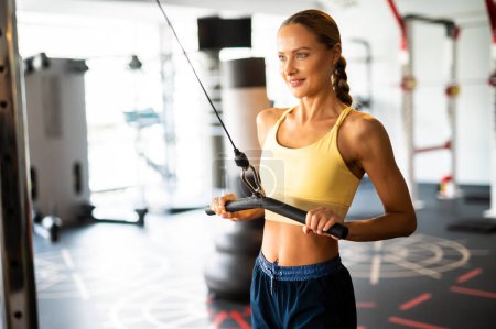 Photo pour Femme utilisant une machine pour s'entraîner dans une salle de gym - image libre de droit