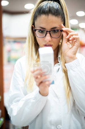 Foto de Joven farmacéutica analizando un producto en su tienda - Imagen libre de derechos