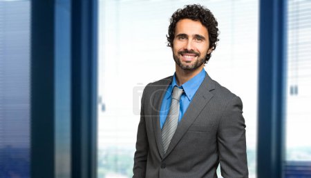 Téléchargez les photos : Portrait d'un bel homme d'affaires dans un bureau moderne - en image libre de droit