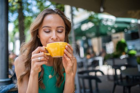 Photo for Smiling woman having breakfast outdoor in a city - Royalty Free Image