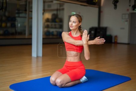 Foto de Mujer haciendo un ejercicio de estiramiento en el suelo en un gimnasio - Imagen libre de derechos