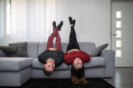 Téléchargez les photos : Couple à l'envers sur le canapé dans leur appartement - en image libre de droit