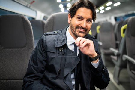 Téléchargez les photos : Portrait d'un manager souriant assis dans un train - en image libre de droit