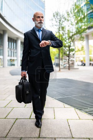 Téléchargez les photos : Homme d'affaires chauve élégant senior marchant avec son sac - en image libre de droit