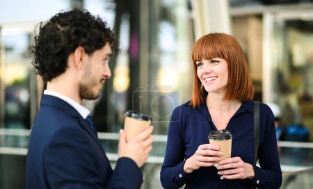 Téléchargez les photos : Partenaires commerciaux discutant ensemble en plein air dans un cadre urbain moderne pendant une pause café - en image libre de droit