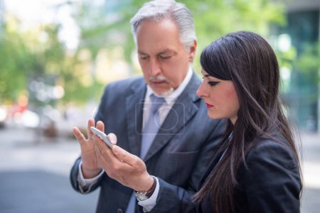 Téléchargez les photos : Les gens d'affaires utilisant un smartphone extérieur - en image libre de droit