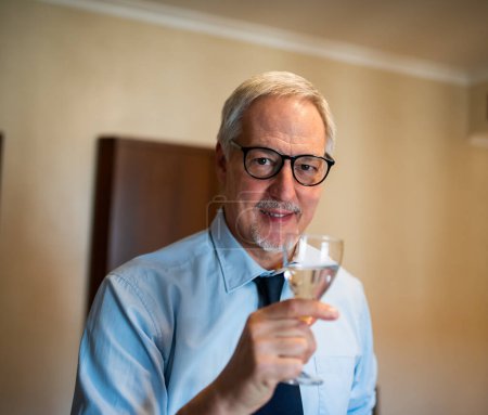 Foto de Un hombre de negocios sonriente bebiendo una copa de vino blanco espumoso - Imagen libre de derechos