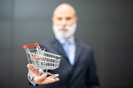 Photo for Businessman showing a shopping cart, e-commerce and entrepreneurship concept - Royalty Free Image