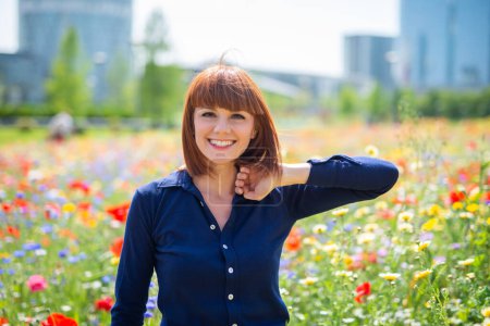 Photo for Joyful woman in a flowers field in a city park - Royalty Free Image