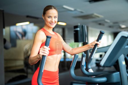 Woman exercising in a gym with an elliptical cross trainer