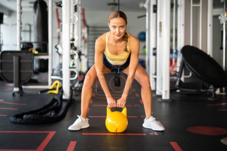 Photo for Woman training in a gym using a kettlebell ball - Royalty Free Image