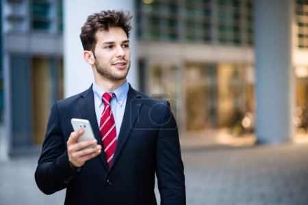 Photo for Handsome young manager using a smartphone outdoor - Royalty Free Image