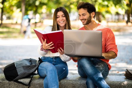 Photo for Two students studying together sitting on a bench outdoor - Royalty Free Image